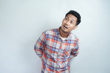 Adult Asian man wearing flannel shirt looking above him with surprised expression