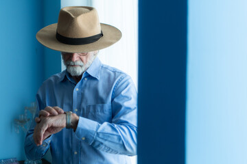 Smiling senior cowboy with watch and stylish hat