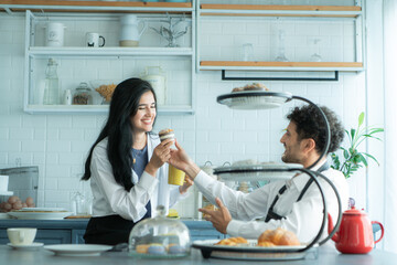 A husband wears an apron while cooking dinner with his wife. The duo took a break to sip coffee and sample the completed bread.