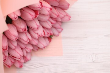 Bouquet of beautiful pink tulips on white wooden table, above view. Space for text