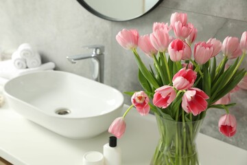 Vase with beautiful pink tulips near sink in bathroom, closeup