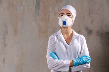 A woman in white lab coat and blue gloves is wearing mask