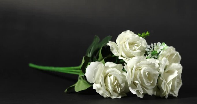 Indian human hand picking up white rose bouquet and gift box from black background. closeup