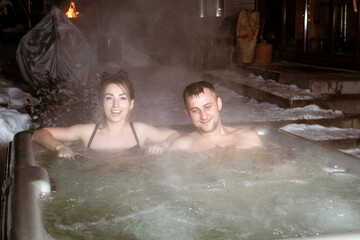 A man and woman are in hot tub, smiling and enjoying steamy water