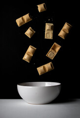 Chocolate candies fall into a white bowl. on a black background. sweets