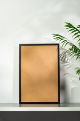 Black wooden photo frame and plant on gray background