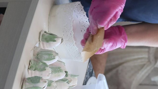 A woman sprinkles powdered sugar on marshmallow flowers. Marshmallow lilies. Homemade marshmallows. Vertical video.