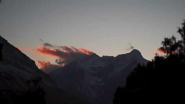 4K Time-lapse shot of orange clouds above the snow covered Himalayan mountain during the sunset as seen from Tayul Monastery near Keylong in Lahaul Valley, Himachal Pradesh, India. Sunset background.
