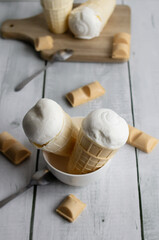 Vanilla ice cream in waffle cones on a white wooden background. dessert