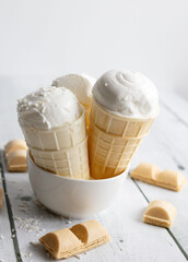 Vanilla ice cream in waffle cones on a white wooden background. dessert