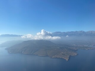 top view of an island in the sea with clouds and mountains on a sunny day