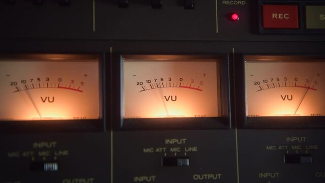 Close up shot of the VU meters on a vintage tape recorder in the recording studio