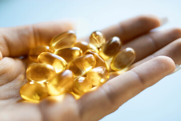 Close-up medicine yellow transparent pills, omega 3 fish oil capsules, vitamin D. Many yellow transparent capsules in hand close-up. The concept of health, vitamins, and medicine