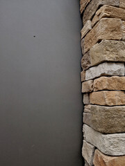 Modern gray brown, beige, metal door at the house lined with stone cladding. gutter for drainage of water on the pavement. limestone cladding