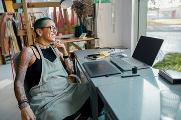 Female worker uses graphics tablet and laptop for retouching photos or digital drawing in studio