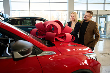 Young guy gives his wife a red car