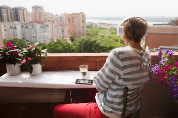 Audio healing. Senior woman in headphones listens to audio recordings from the phone on a balcony...