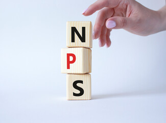 NPS - Net Promoter Score symbol. Wooden cubes with words NPS. Businessman hand. Beautiful white background. Business and NPS concept. Copy space.