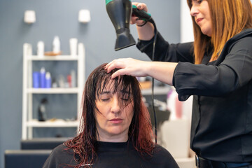 Fototapeta premium Hairdresser drying the hair of a patient woman
