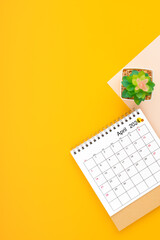 Calendar page for April 2024 and houseplant on yellow background.