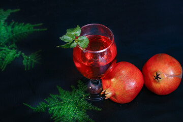 ripe pomegranate and glass of wine on Black background. Background has Flowers