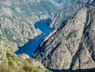 Wonderful landscape of the Ribeira Sacra with a tourist boat sailing through the canyons of the Sil River. Galicia, Spain.