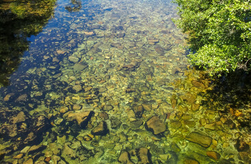 Crystal clear and greenish waters of a river in the background can be seen full of boulders. A Lama, Galicia, Spain.