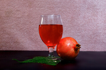 ripe pomegranate and glass of wine on Rose background