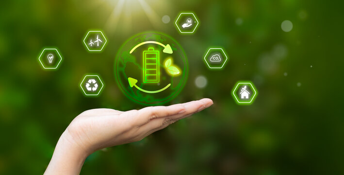 Renewable energy with wireless battery charging icon on smartphone. Hand holding mobile phone and touching on virtual saving icon near laptop, eco-friendly device, and environment technology concept. - Powered by Adobe