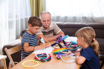 grandfather and two grandchildren make a 3d plastic robot craft together with a 3d pencil