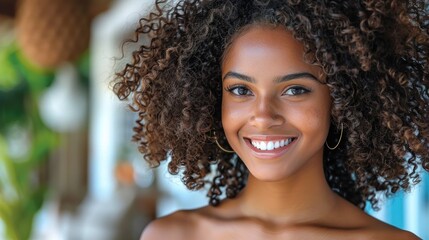 A woman with curly hair smiling directly at the camera - obrazy, fototapety, plakaty