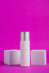 Plastic white tube for cream or lotion. Skin care or sunscreen cosmetic with stylish props on purple background 