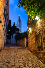 beautiful street of Rovinj Croatia with cobblestone and church tower dusk