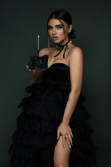Young celebrating woman black dress . Beautiful model portrait isolated over studio background hold birthday cake