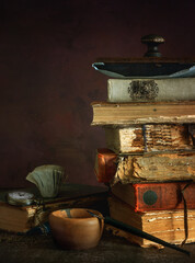 Old, shabby books and a pen with a feather and inkwell.
