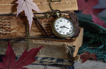 Pocket watch with a chain against the background of old, tattered books. Vintage.