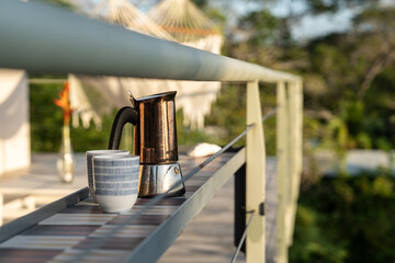 Kaffeepause auf der Terrasse im Sonnenaufgang mit Frenchpress und Kaffeetassen im Bild