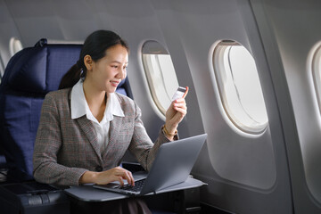 Asian female using laptop computer and holding credit card in airplane, Business traveling and...