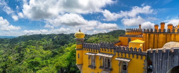 Wide angle exterior view of the top of the yellow watchtower and attic of the Pena Palace, under a...