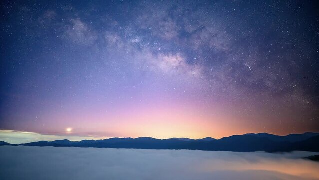 Capture the mesmerizing dance of the Milky Way, dynamic cloud formations, and vibrant neon lights behind layered mountain ranges. Xindian, Taiwan.