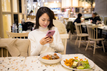 Woman use mobile phone to take photo on her food in restaurant