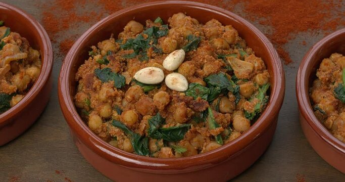 Homemade Spinach and Chickpeas (Espinacas con Garbanzos) with smoked paprika seasoning scattered on a table. Table spin. 