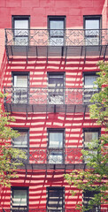 Facade of a building with fire escape balcony, color toning applied, New York City, USA.
