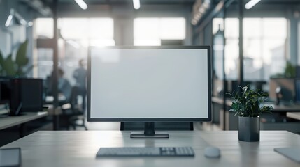 A mockup featuring a blank white screen monitor set against a backdrop of a modern office workspace.