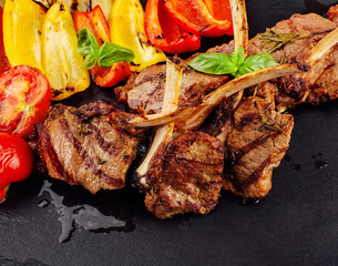 Grilled lamb chops with vegetables on a stone board