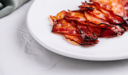 Plate with tasty bacon slices on stone