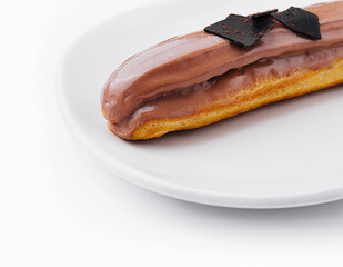 Eclair topped with chocolate on white plate