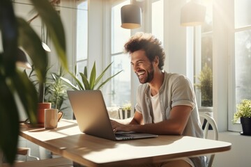 Man working on laptop, sunny home office, cheerful. - obrazy, fototapety, plakaty