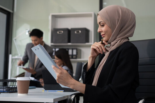 muslim business woman wearing hijab checking working schedule plan at her working desk.