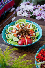 Mushrooms with mixed green salad and black olives. Cut the onion into circles. Food arranged on blue ceramic plates on a wooden table. Front view from above. atmosphere in the garden